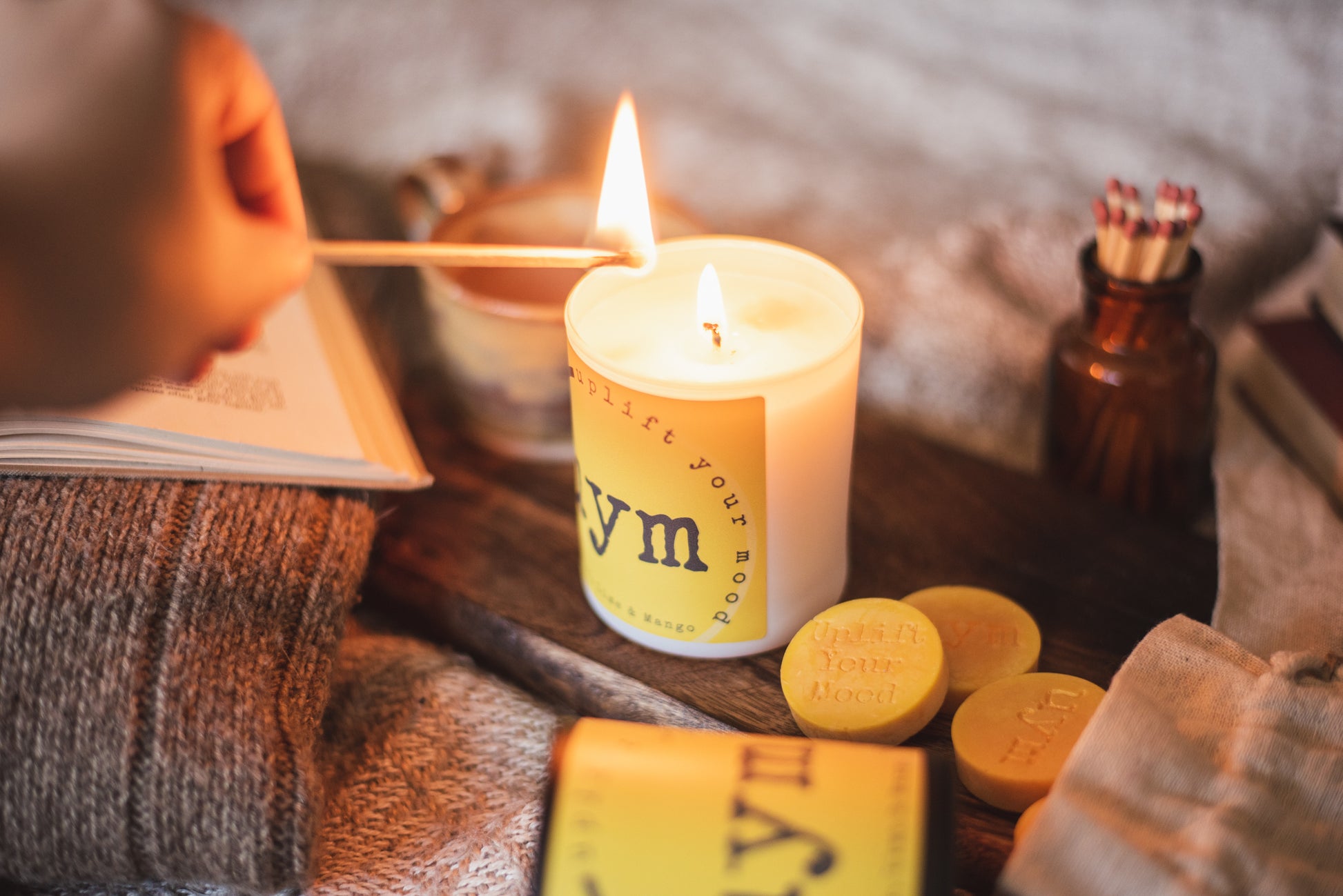 Thai Lime and Mango natural wax candle, matt white glass jar candle lighted, natural wax melts yellow in a cotton bag, apotecary glass with matches,  cosy atmosphere, Uplift Your Mood Scents